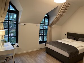 Un dormitorio con una cama, un escritorio y dos ventanas con cortinas.