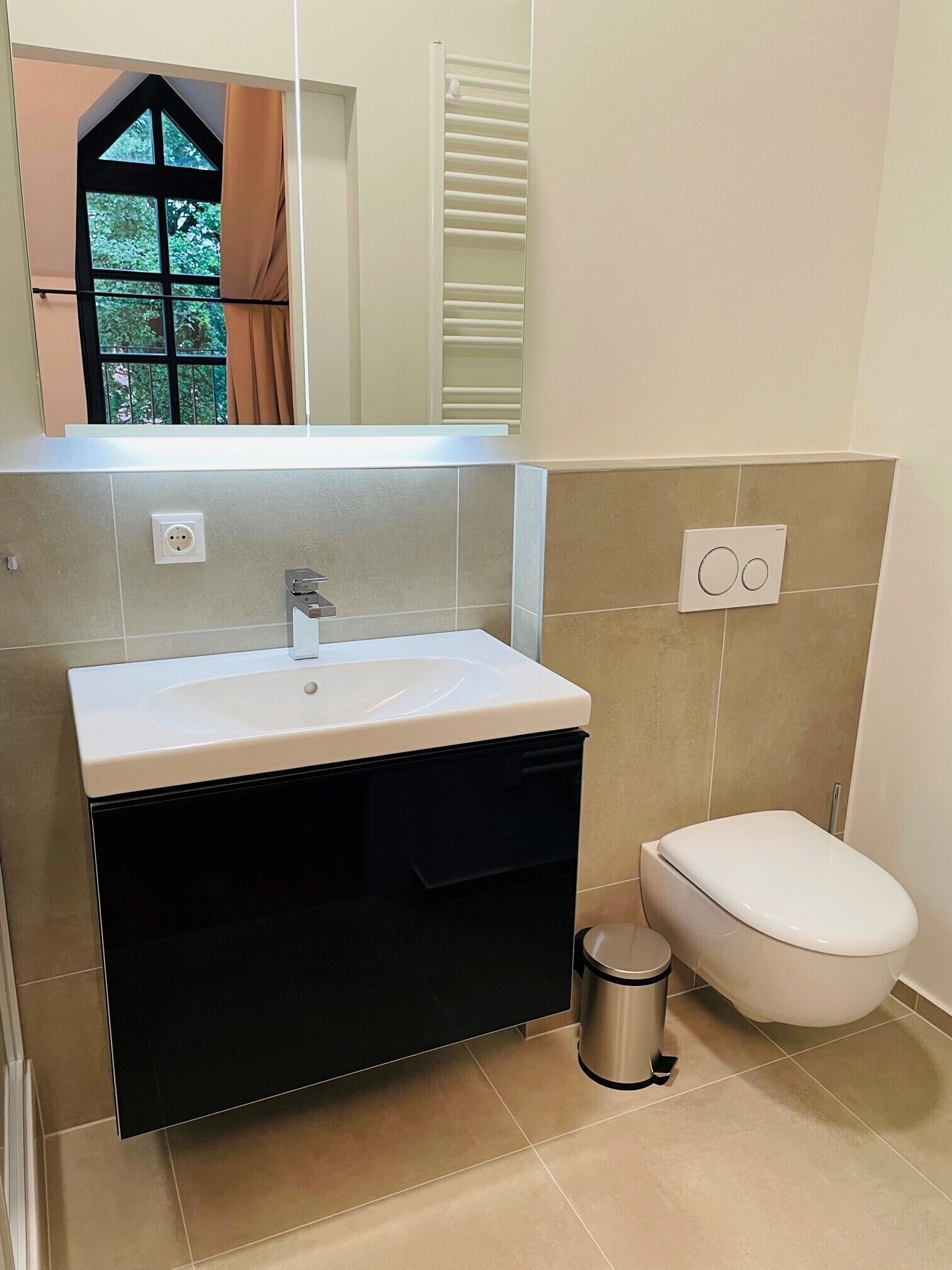 A bathroom with a white sink, black cabinet, and a white toilet.
