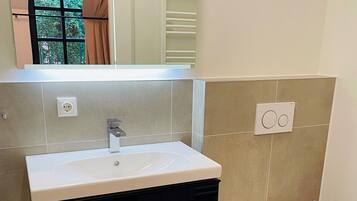 A bathroom with a white sink, black cabinet, and a white toilet.