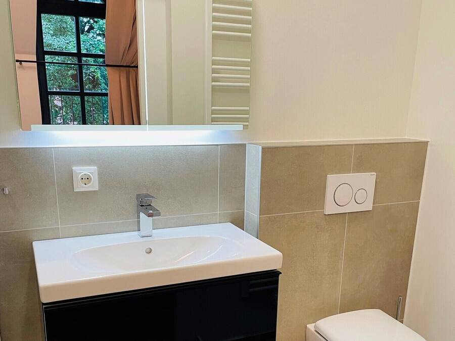 A bathroom with a white sink, black cabinet, and a white toilet.