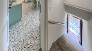 Um corredor com piso ladrilhado que leva a uma escada e uma porta.