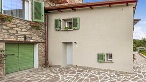 Um edifício de dois andares com paredes de pedra, uma porta verde e persianas.