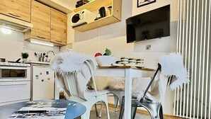A modern kitchen with white cabinetry, a built-in oven, and a dining area with white chairs and a table. - Studio cabin with south balcony, 5 min to slopes, wifi included (Tignes)