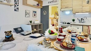 A cozy living room with a sofa, a small table with snacks, a teddy bear, and a bookshelf. - Studio cabin with south balcony, 5 min to slopes, wifi included (Tignes)