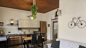 A modern kitchen with a dining area, a sofa, and a bicycle decoration on the wall.