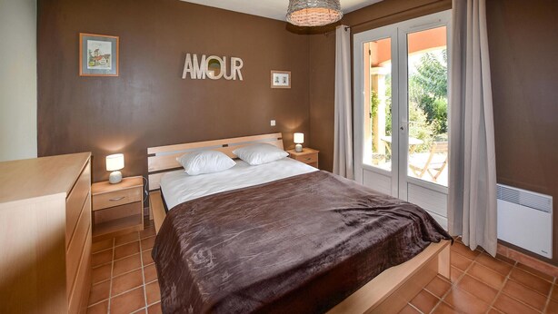 A bedroom with a bed, nightstands, a lamp, a framed picture, and a window with curtains. - Beautiful home in Mazan with WiFi (Mazan)