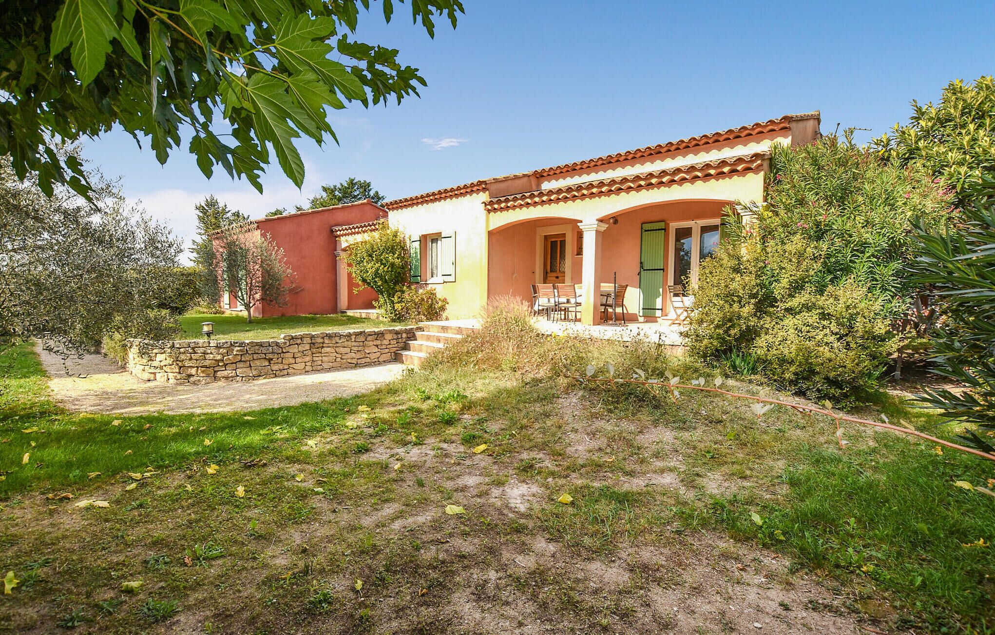 Ein zweistöckiges Haus mit Terrasse, Steinmauer und Garten.