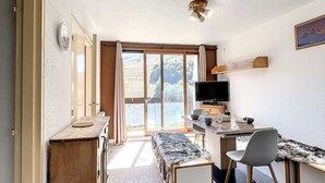 Une pièce comprenant un bureau en bois, une chaise, un téléviseur et un banc.