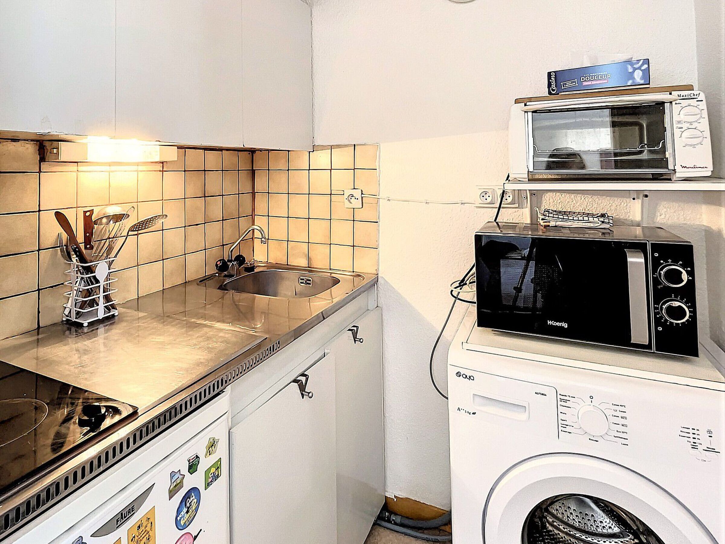 Una cocina compacta con lavamanos, estufa, microondas y lavadora.