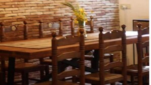 A dining area with a brick wall, wooden chairs, and hanging pendant lights. - Bakit House - Casa Rural con Piscina Privada (Águilas)
