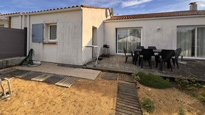 Ein Wohngebäude mit Terrasse, inklusive Tisch und Stühlen, einer Schiebetür und einer Satellitenschüssel.