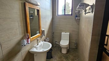 Une salle de bain avec un lavabo, un miroir, des toilettes et une fenêtre.