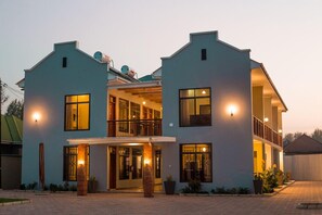 A two-story building with a balcony on the upper floor, large windows, and a well-lit entrance. - Medan Hotel & Apartments (Arusha)