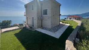 A two-story stone building with a flat roof, a small balcony, and a paved area in front. - Family Vacation Villa Rezevici (Petrovac)