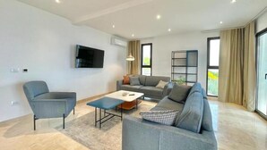 A modern living room with a grey sofa, a blue armchair, and a coffee table. - Family Vacation Villa Rezevici (Petrovac)