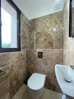 Une salle de bain avec des toilettes, un lavabo et une fenêtre.