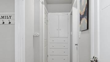 Un pasillo estrecho con una puerta blanca al final que da a una habitación con un armario.