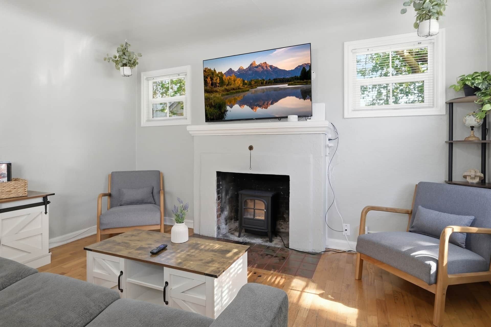 Una sala de estar con chimenea, dos sillones, una mesa de centro y un televisor montado sobre la chimenea.