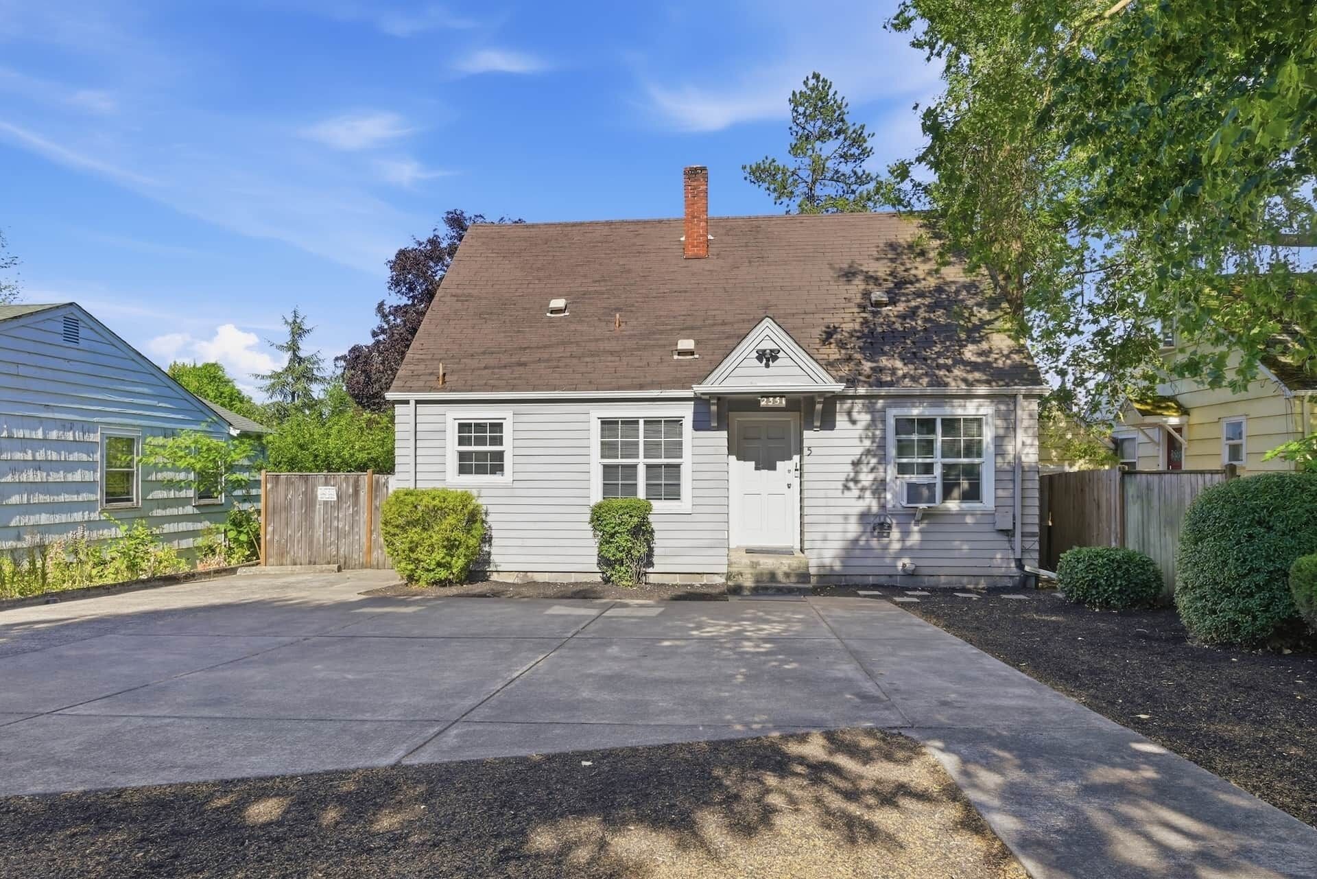 A single-story house with a front porch, a chimney, and a small front yard.