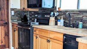 A kitchen with wooden cabinets, a black stove, a microwave, and a dishwasher. - Quiet and Unique 2BR on Winery Row - The Elgin Project (Elgin)