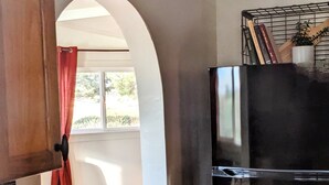 A kitchen with a black refrigerator, a wooden cabinet, and a window with a red curtain. - Quiet and Unique 2BR on Winery Row - The Elgin Project (Elgin)