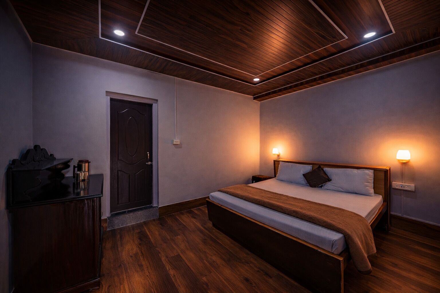 A bedroom with a wooden bed, bedside lamps, a nightstand, and a dark wooden dresser.
