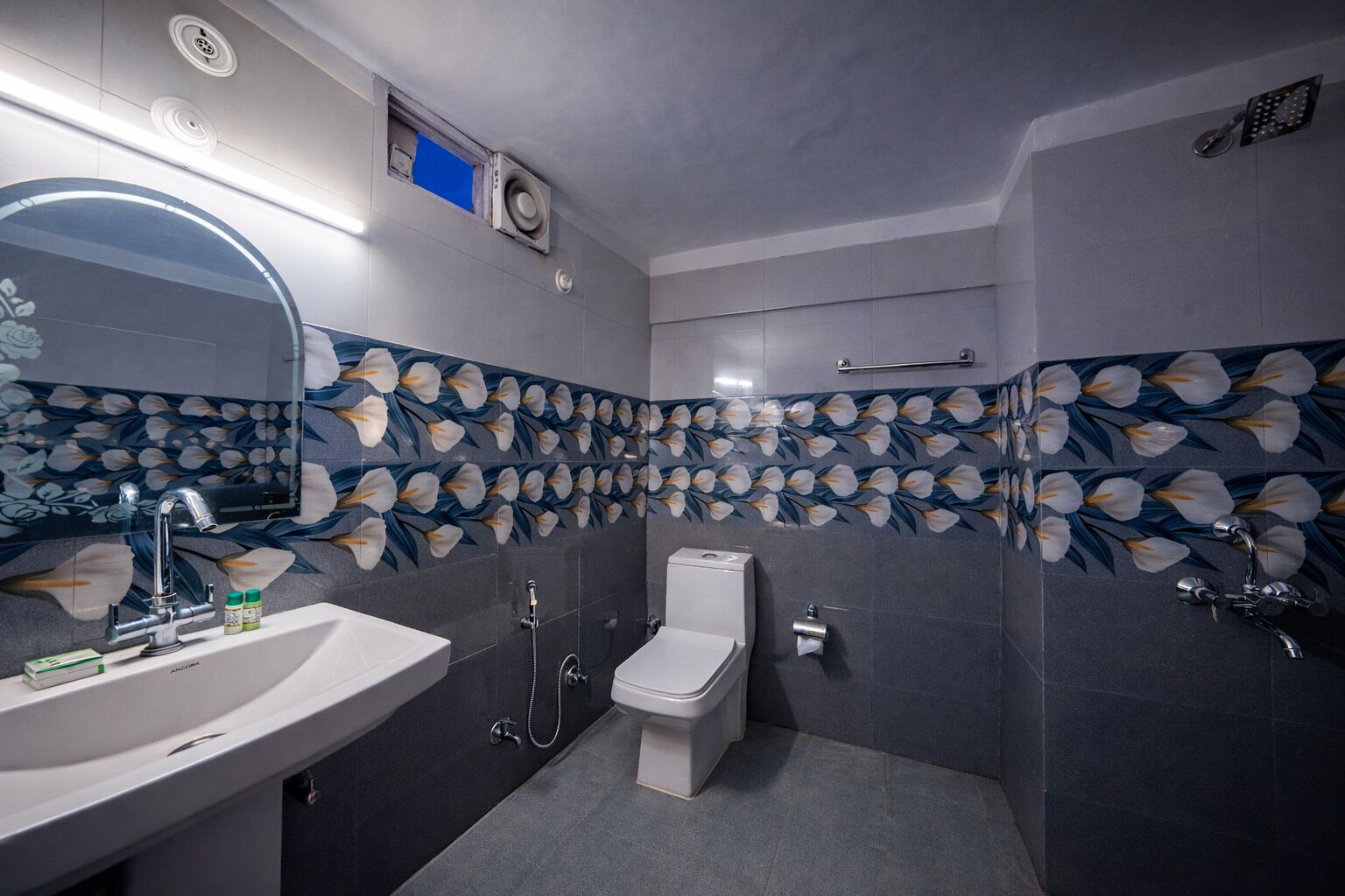 A bathroom with a toilet, sink, shower, and a mirror.