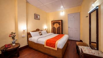 Un dormitorio con una cama de madera, mesitas de noche, un tocador, un espejo y una puerta.