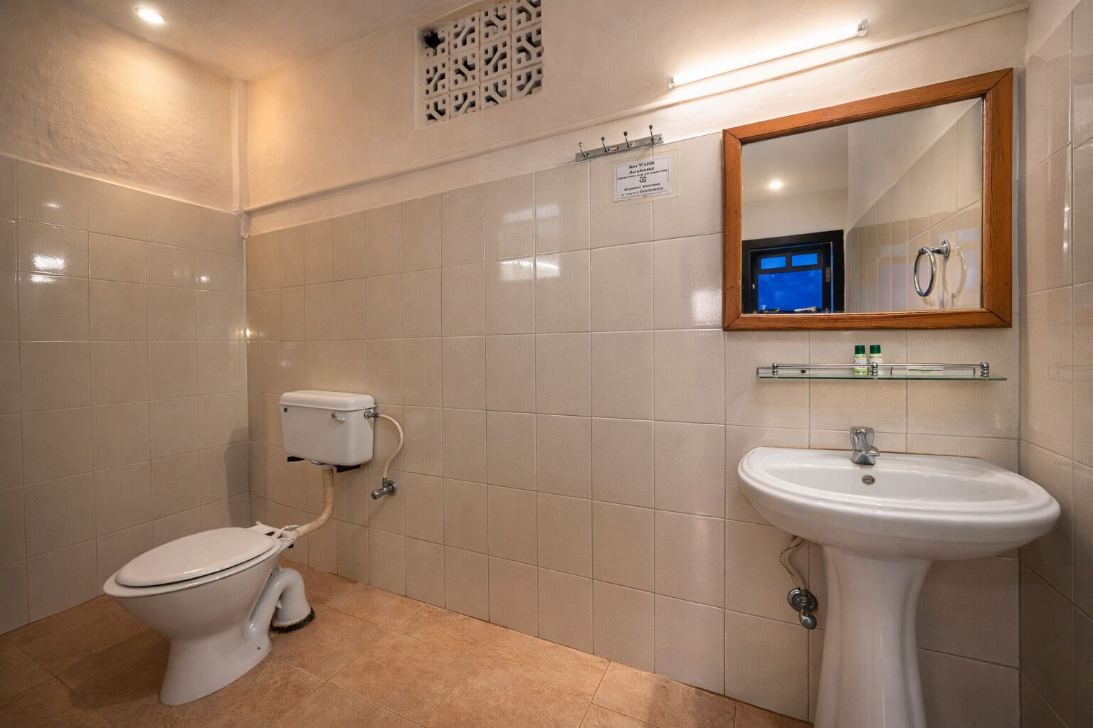 Une salle de bain avec des toilettes, un lavabo et un miroir.
