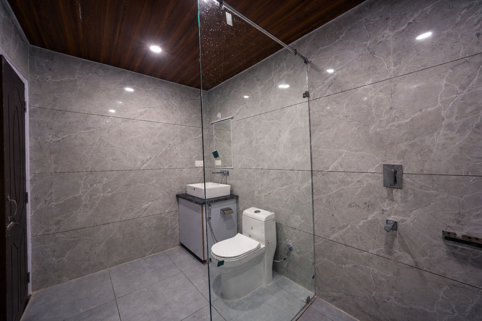 Ein modernes Badezimmer mit einer Duschkabine aus Glas, einem weißen Waschbecken und einer Toilette.