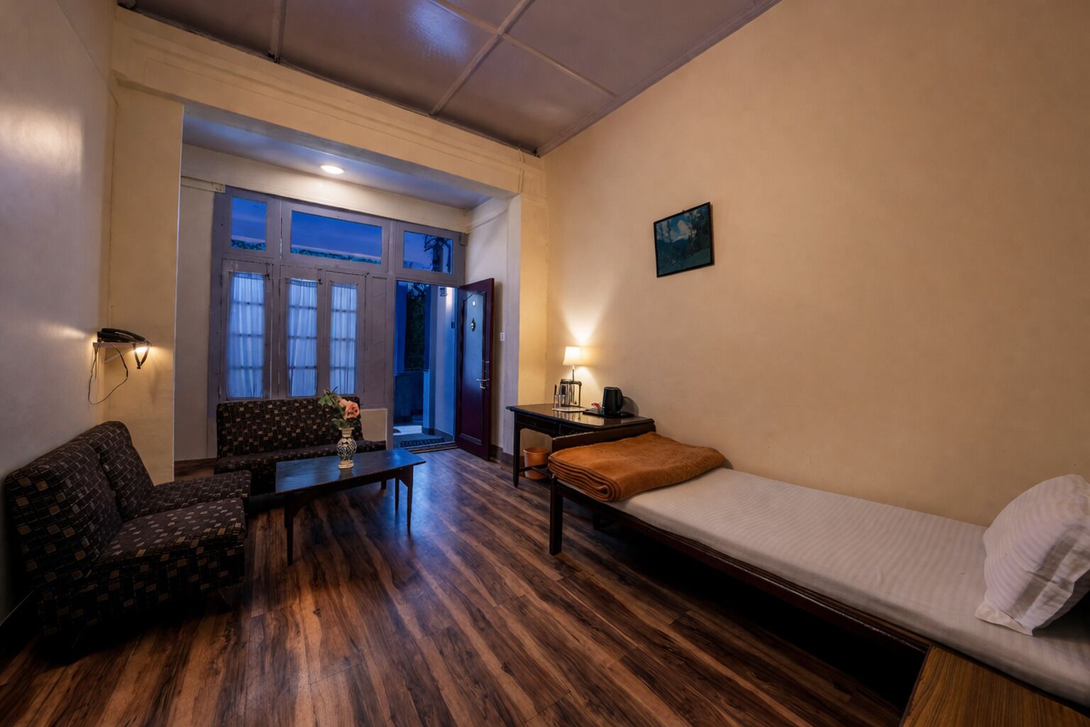 Habitación con cama, sofá, mesa y una silla. Hay una puerta que da a un espacio al aire libre.