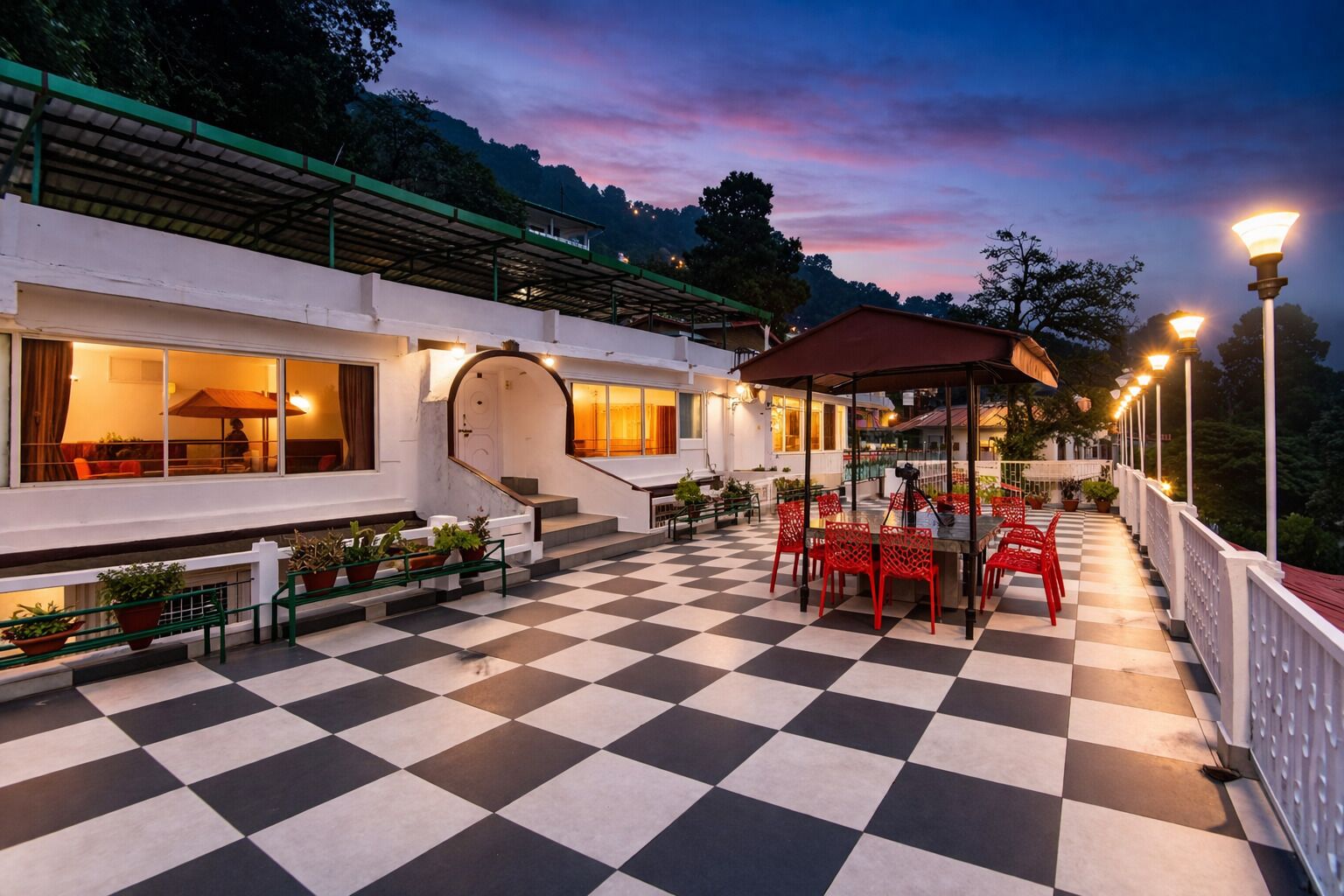A hotel with a checkered outdoor patio, a covered seating area, and a staircase leading to an upper level.