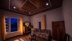 A room with a wooden ceiling, a sofa, a table with a vase, and a cabinet. - India Hotel - Mall Road Nainital - Lake View (Nainital)
