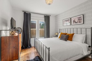 Un dormitorio con una cama, un aparador de madera, un espejo y una ventana con cortinas.