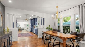 A modern kitchen with dark cabinets, a wooden dining table, and a chandelier.
