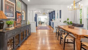 A modern kitchen with dark cabinets, a wooden dining table, and a chandelier.