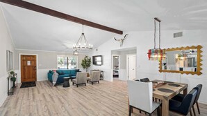 A spacious living area with a dining table, sofas, and a large mirror. - Fritztown's Finest - Hot Tub, Fire Pit & Sleeps 10 (Fredericksburg)