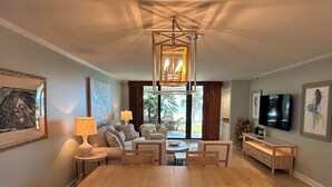 Un ampio soggiorno con tavolo da pranzo in legno, comodi posti a sedere, TV e opere d'arte alle pareti.