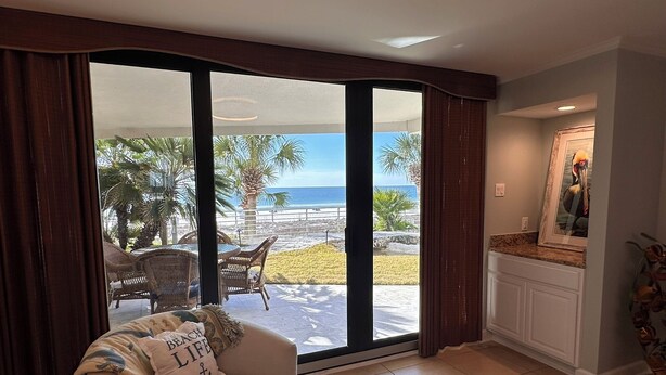 Un soggiorno con una porta scorrevole in vetro che dà su un patio con vista sulla spiaggia e sull'oceano.