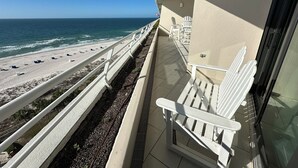 A balcony with a white chair, a view of the beach, and a railing. - Eden W 902 Gulf Front Condo with Stunning Views! (Pensacola)