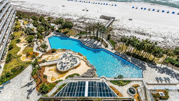A resort with a large swimming pool, beach area, and palm trees. - Eden W 902 Gulf Front Condo with Stunning Views! (Pensacola)