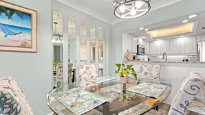 A dining area with a glass table, patterned placemats, and chairs with floral upholstery. - FAMILY FAVORITE!! NEW UPGRADES!  Booking for Summer NOW! (Myrtle Beach)