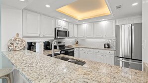 A modern kitchen with white cabinetry, granite countertops, stainless steel appliances, and a skylight. - FAMILY FAVORITE!! NEW UPGRADES!  Booking for Summer NOW! (Myrtle Beach)