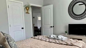 Une chambre à coucher avec un lit, une télévision et un miroir au mur.