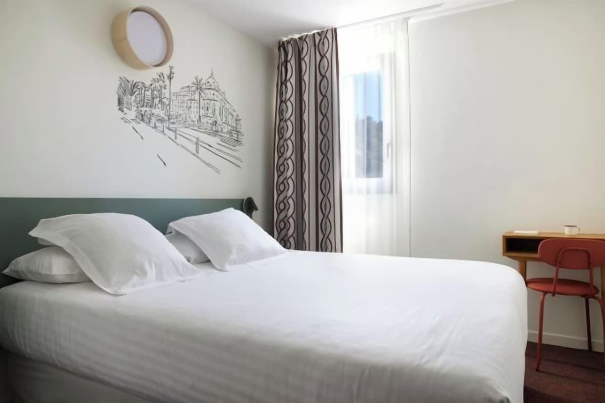 A hotel room with a bed, a desk, and a chair.