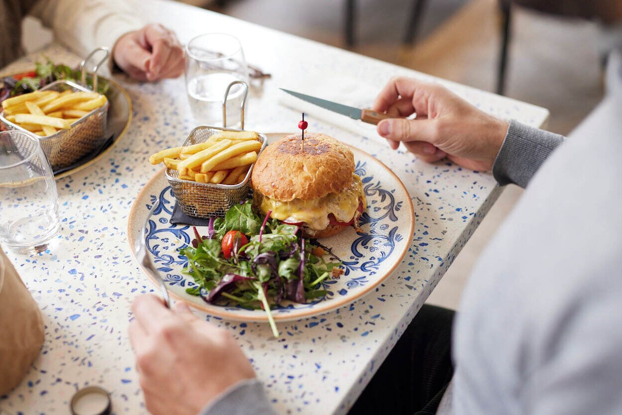 A dining table with a plate of food, including a burger and fries, and a glass of water.