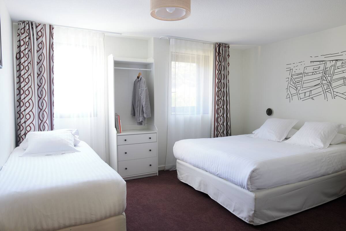 Une chambre d’hôtel avec deux lits, une armoire et un miroir.