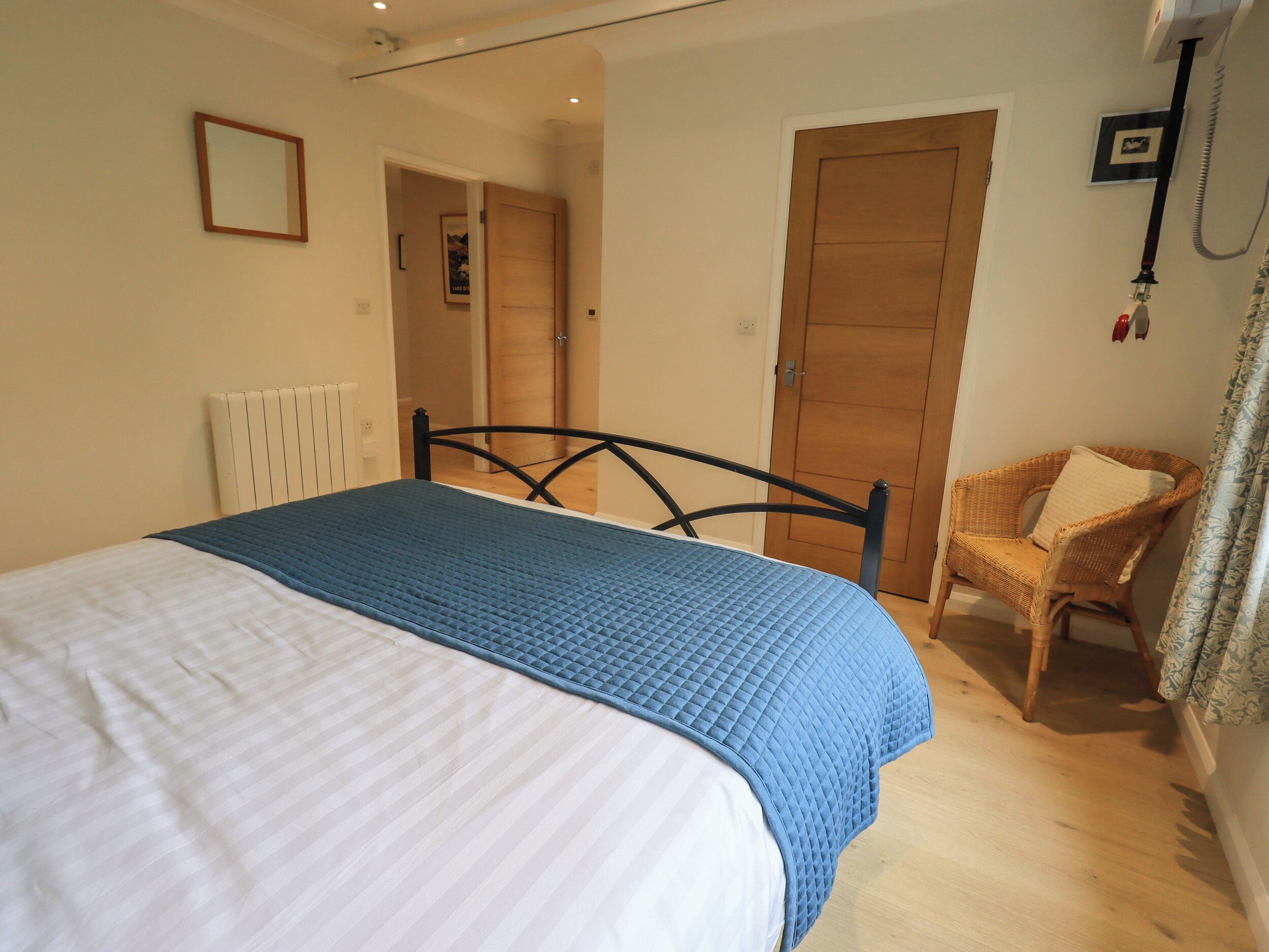A bedroom with a bed, a chair, a door, and a radiator.