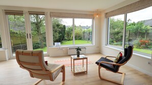 A spacious room with large windows, a radiator, a small table, and two chairs. - Pembroke (Grange-over-Sands)