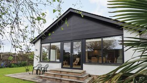 A modern house with a large glass window, a small porch, and a garden. - Pembroke (Grange-over-Sands)